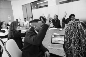 Business people with raised hands sitting around a table.