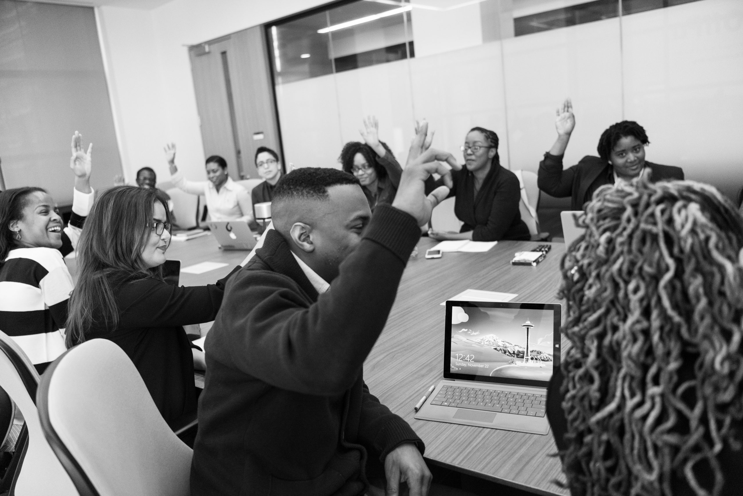Business people with raised hands sitting around a table.