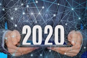 A business man holding a tablet with 2020 on top.