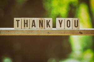 Wooden blocks spell out 'thank you' on a table.