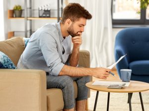 A man reading a document while sitting on a couch.