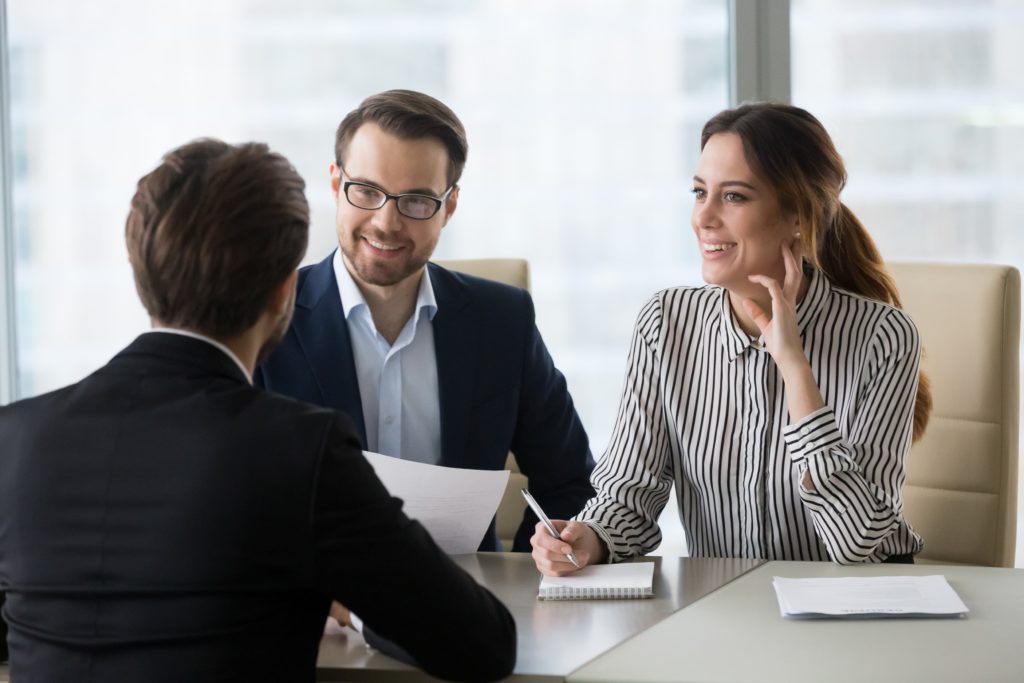 Two people talking with someone across a desk