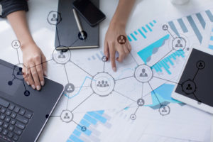 Business person working on laptop, surrounded by social network icons.