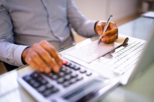 A man using a calculator and writing a check.
