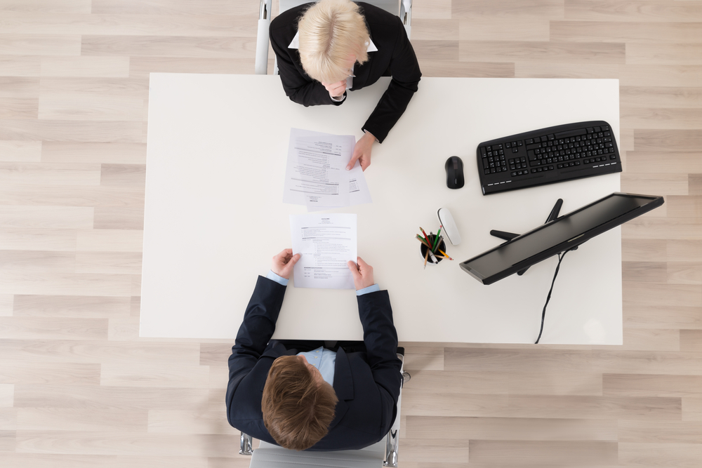 Top view of two business people sitting at a table, engaged in interview.