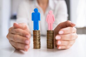 A woman's hands surround two stacks of coins, one with a man and one with a woman on top.