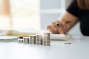 Woman managing finances by counting coins on a table.