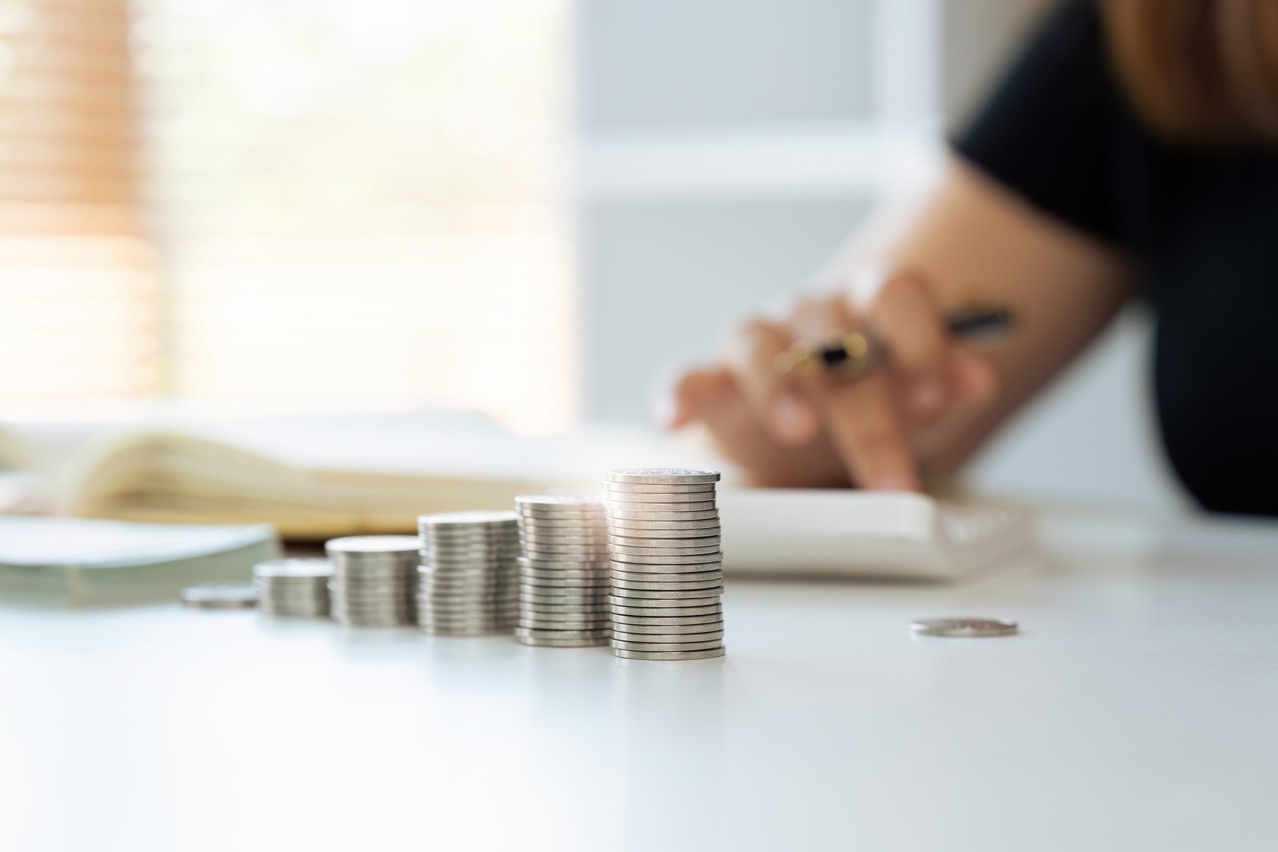 Woman managing finances by counting coins on a table.